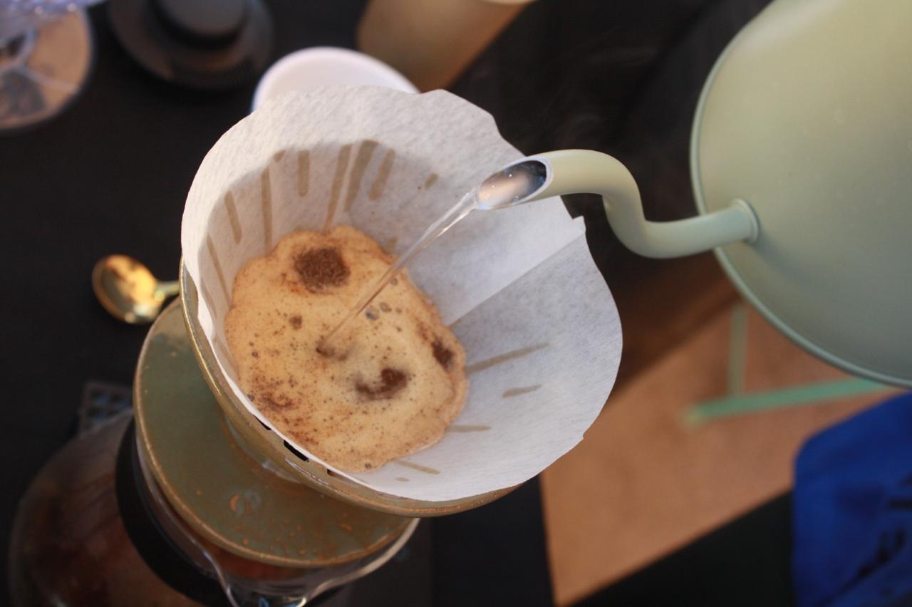 Barista vertiendo agua sobre café molido en un filtro